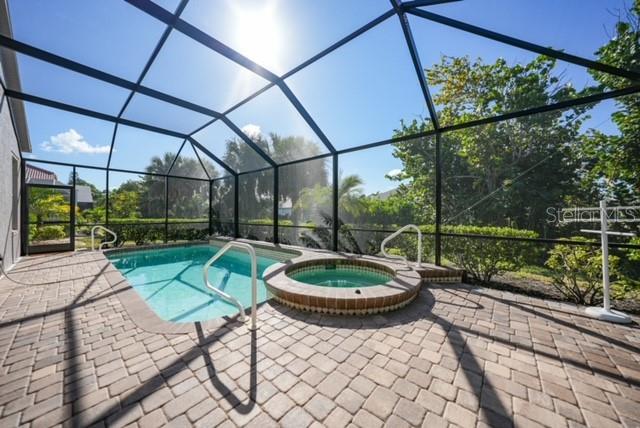 A screened-in patio features a rectangular swimming pool and a circular spa with paver flooring — 17849 HIBISCUS COVE COURT UNIT 1, PUNTA GORDA, FL