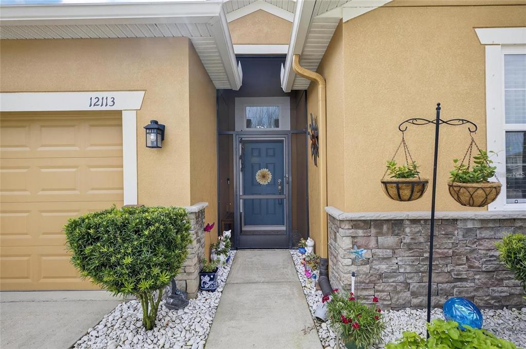 The exterior of a house features a blue front door, stone siding, and a garage — 12113 ECHO BASIN COVE, RIVERVIEW, FL