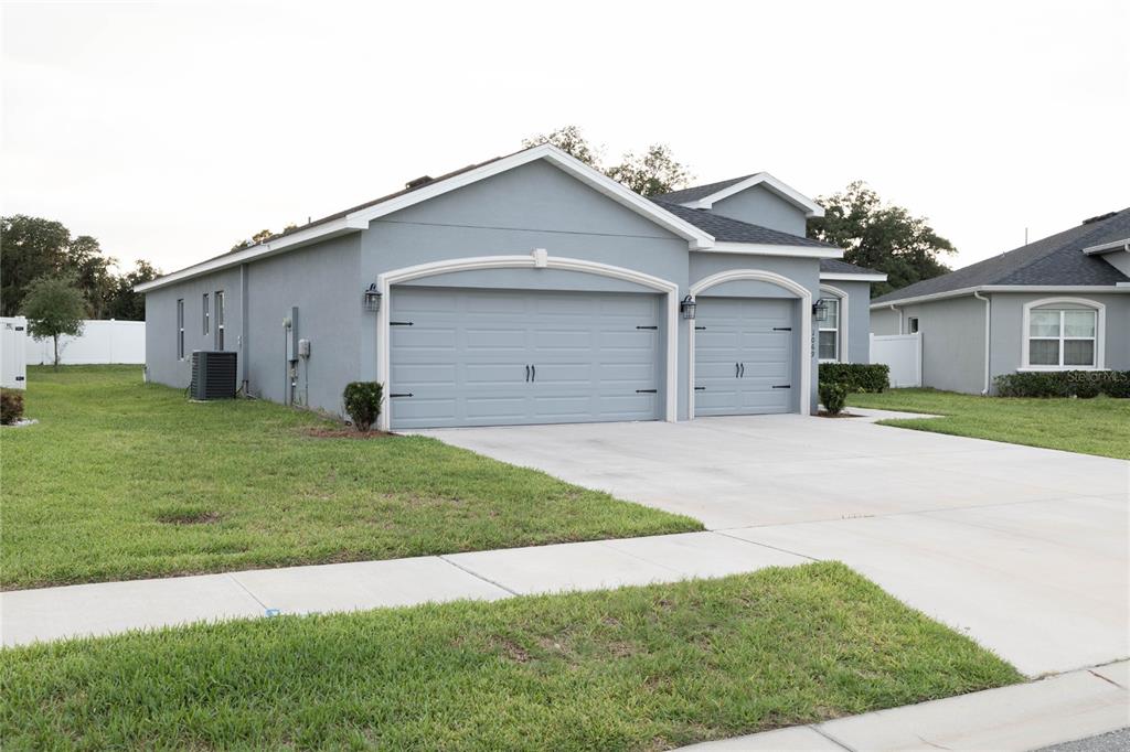 A light blue single-story house features a two-car garage and a concrete driveway — 1069 MONTGOMERY LANE, POLK CITY, FL