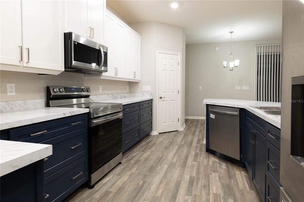 A kitchen features white upper cabinets, dark blue lower cabinets, and marble-look countertops — 1069 MONTGOMERY LANE, POLK CITY, FL
