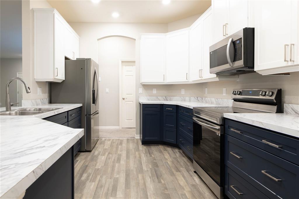 A kitchen with white upper cabinets, dark blue lower cabinets, and marble-patterned countertops — 1069 MONTGOMERY LANE, POLK CITY, FL
