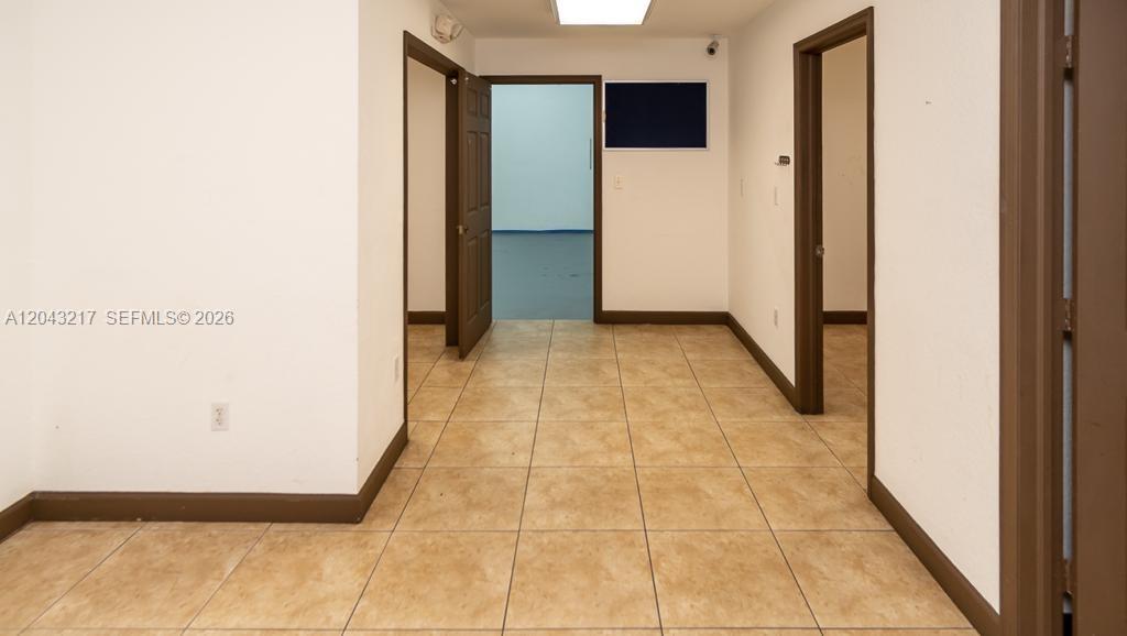 A hallway with tan tile flooring leads to an open doorway and two side rooms — 8248 NW 22nd Ave, Miami FL 33147, MIAMI, FL