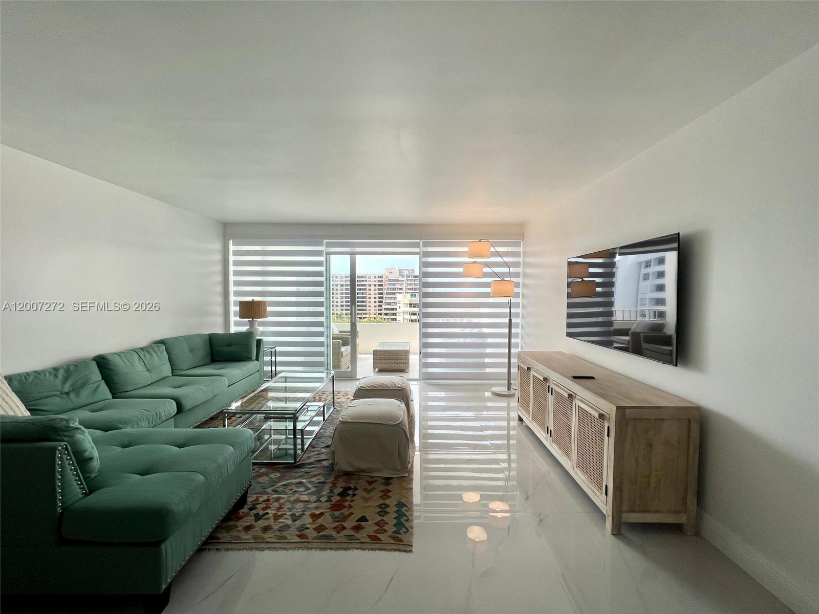 A living room features a green sectional sofa, a glass coffee table, and a television — 155 Ocean Lane Dr # 1011, Key Biscayne FL 33149, KEY BISCAYNE, FL