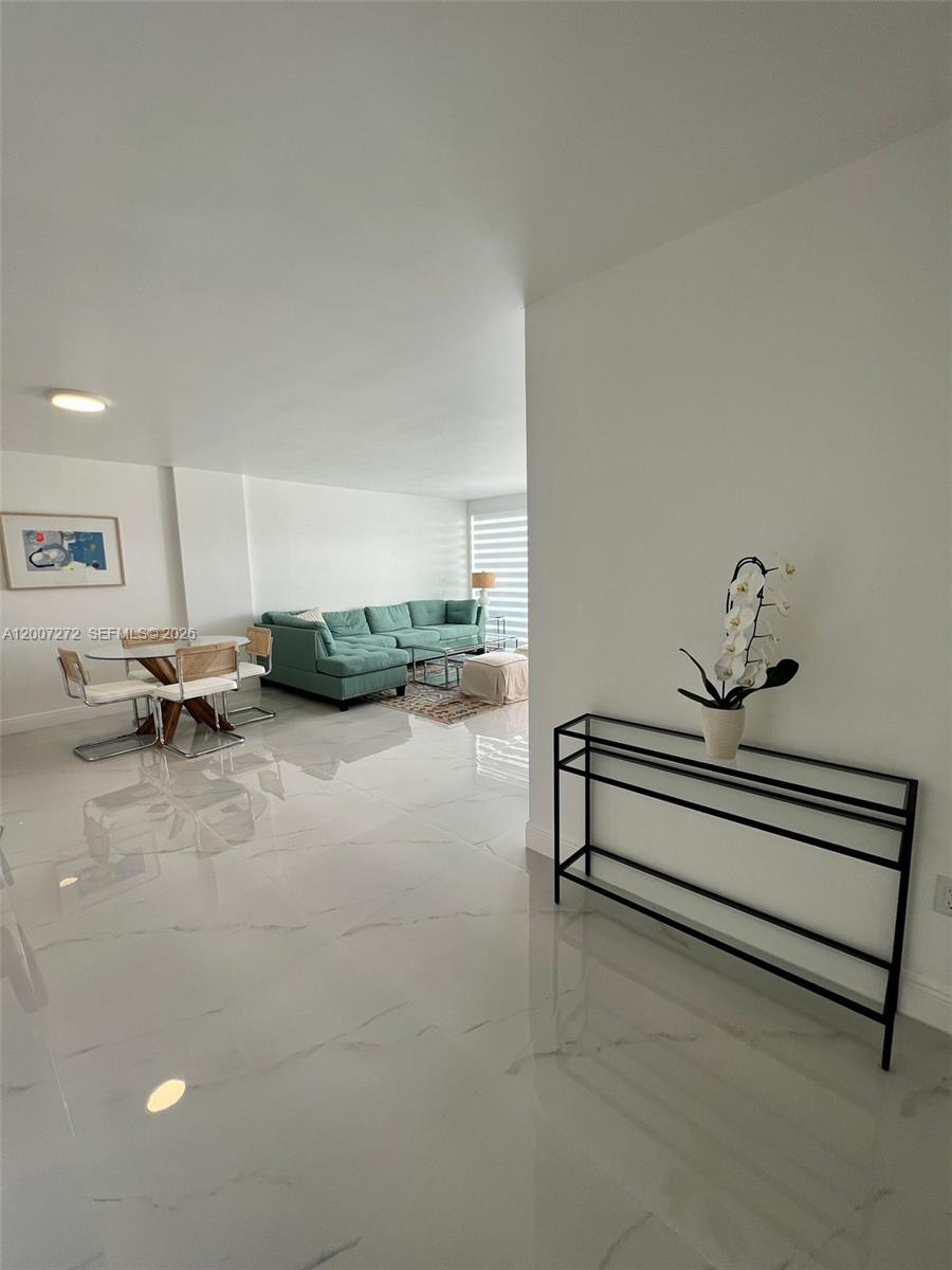 A bright, open-concept living and dining area features white marble floors and a teal sofa — 155 Ocean Lane Dr # 1011, Key Biscayne FL 33149, KEY BISCAYNE, FL