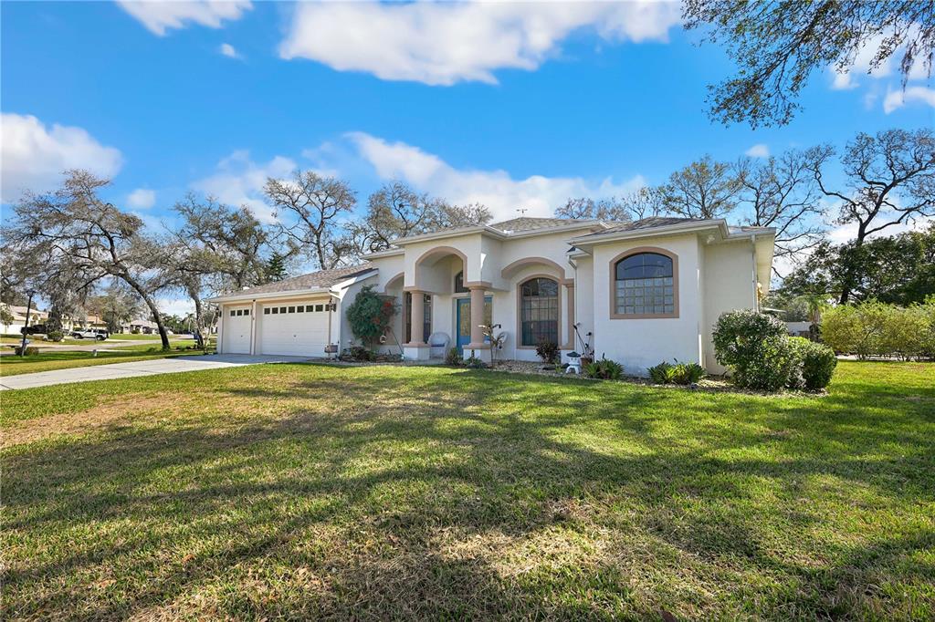 A single-story house with a white stucco exterior, arched entryway, and a two-car garage — 13855 RUDI LOOP, SPRING HILL, FL