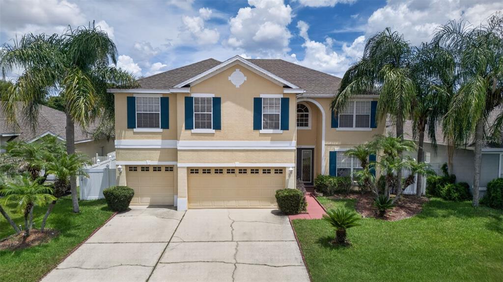 A two-story suburban house with a three-car garage, beige stucco exterior, and palm trees — 417 KEHOE BOULEVARD, ORLANDO, FL