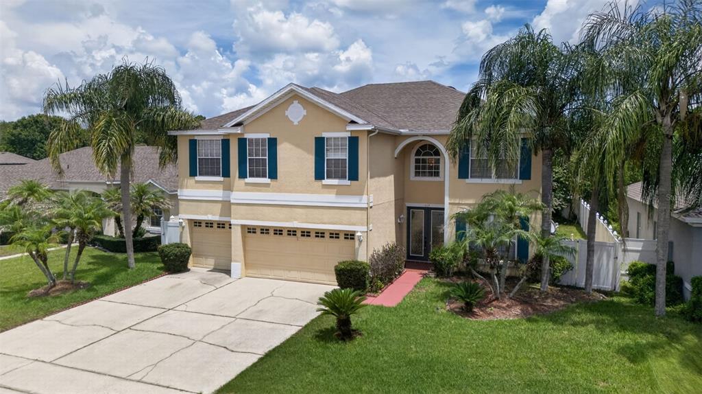 A two-story tan house with blue shutters, a three-car garage, and a palm-lined front yard — 417 KEHOE BOULEVARD, ORLANDO, FL