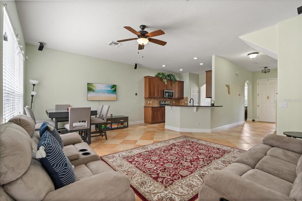 A living room with a red patterned rug, tan sofas, and an open kitchen area — 1530 TALLY CIRCLE, OVIEDO, FL