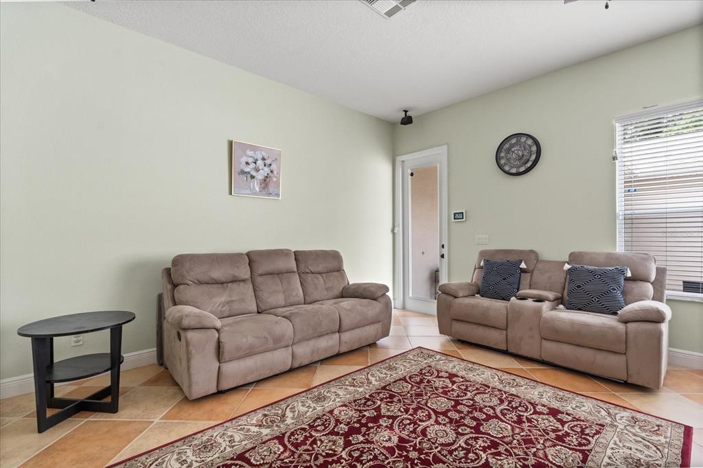 A living room features light green walls, tile flooring, two brown sofas, and a rug — 1530 TALLY CIRCLE, OVIEDO, FL