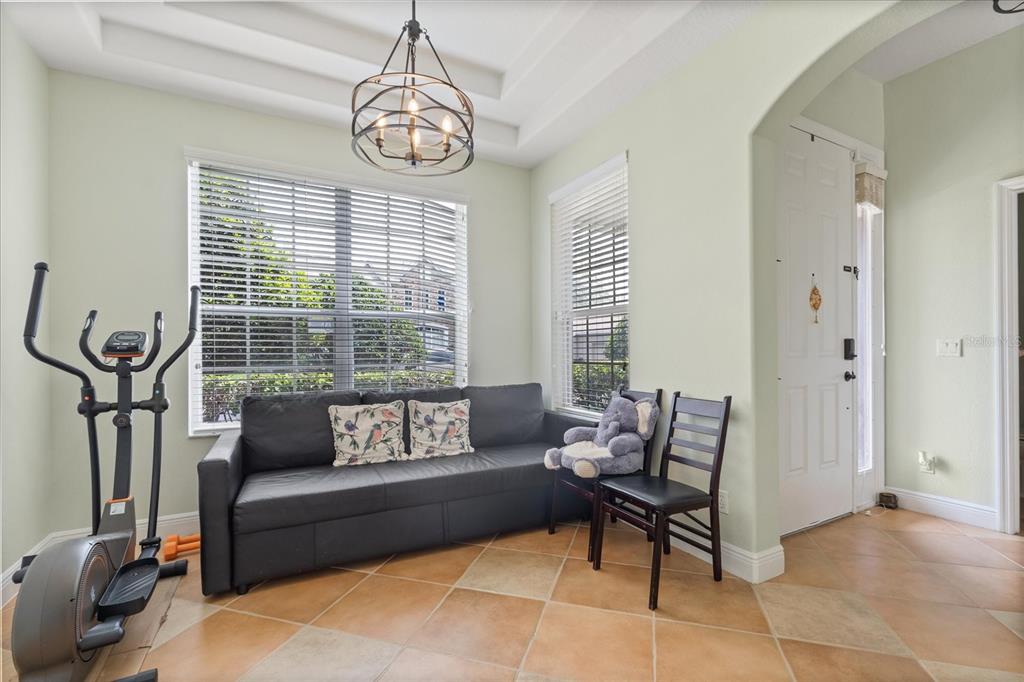 A room with light green walls, tile flooring, a black sofa, and an elliptical machine — 1530 TALLY CIRCLE, OVIEDO, FL