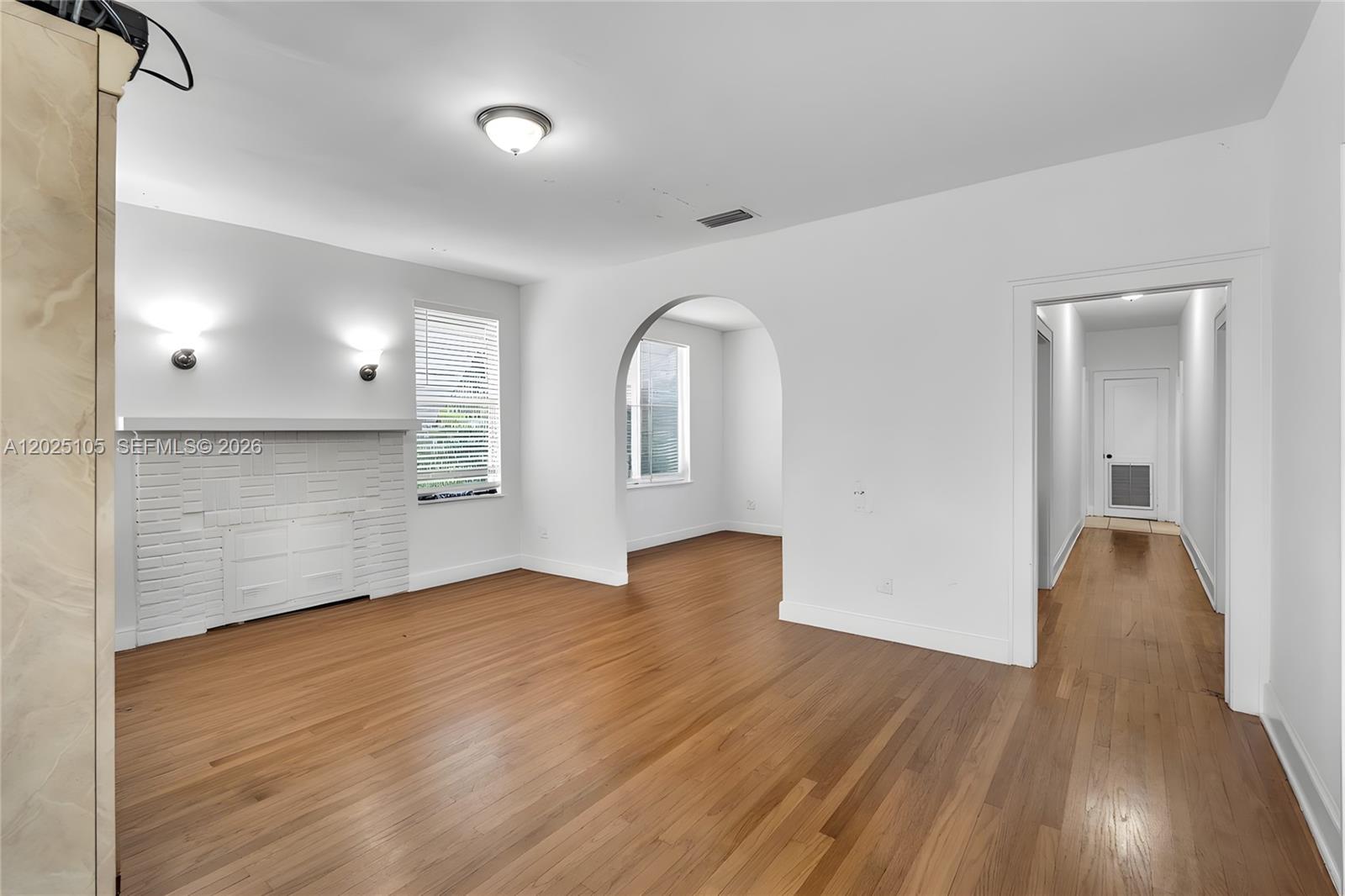 A living room features hardwood floors, a white brick fireplace, and an arched entryway — 137 NW 20th St, Homestead FL 33030, HOMESTEAD, FL