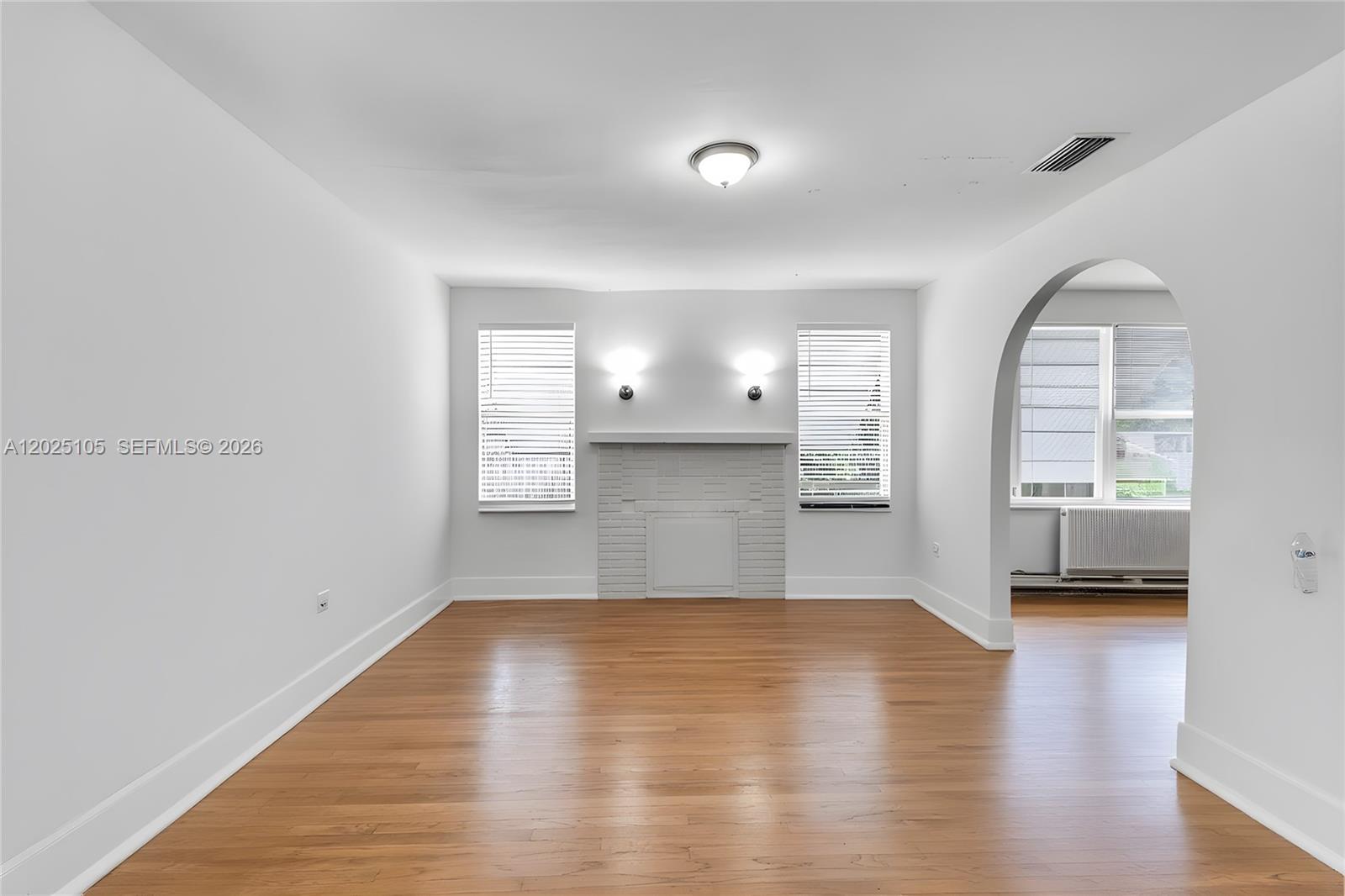 A living room features hardwood floors, a white brick fireplace, and an arched entryway — 137 NW 20th St, Homestead FL 33030, HOMESTEAD, FL