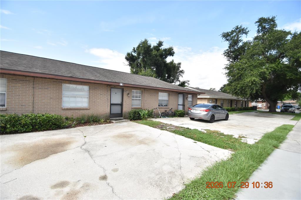 A single-story brick apartment building features a cracked concrete driveway and a parked silver sedan — 409 BIG CEDAR WAY UNIT B, BRANDON, FL