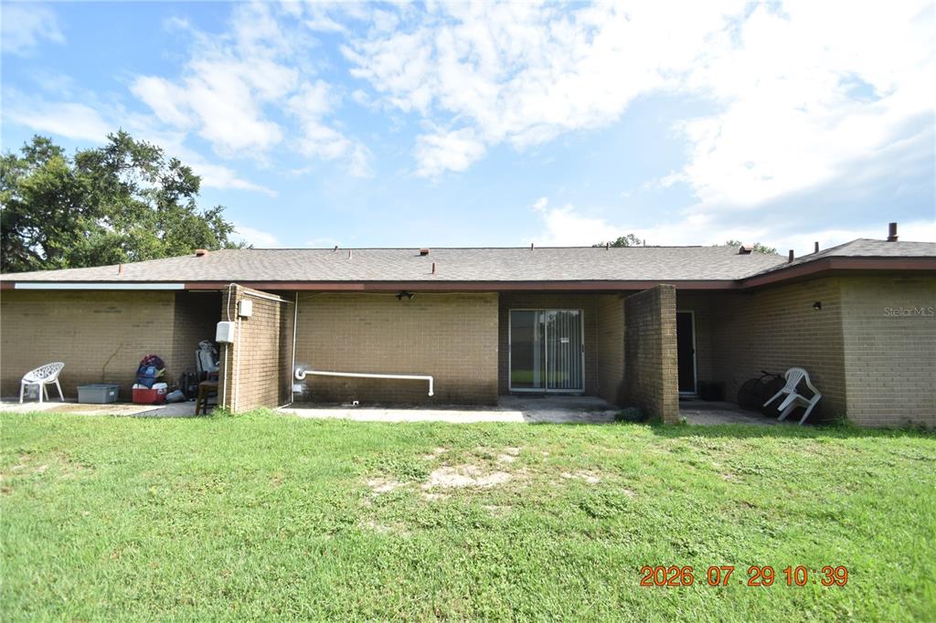 The exterior of a single-story brick house features a patio, sliding glass doors, and lawn — 409 BIG CEDAR WAY UNIT B, BRANDON, FL