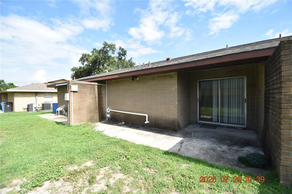 A brick exterior features a concrete patio and a sliding glass door at the rear — 409 BIG CEDAR WAY UNIT B, BRANDON, FL