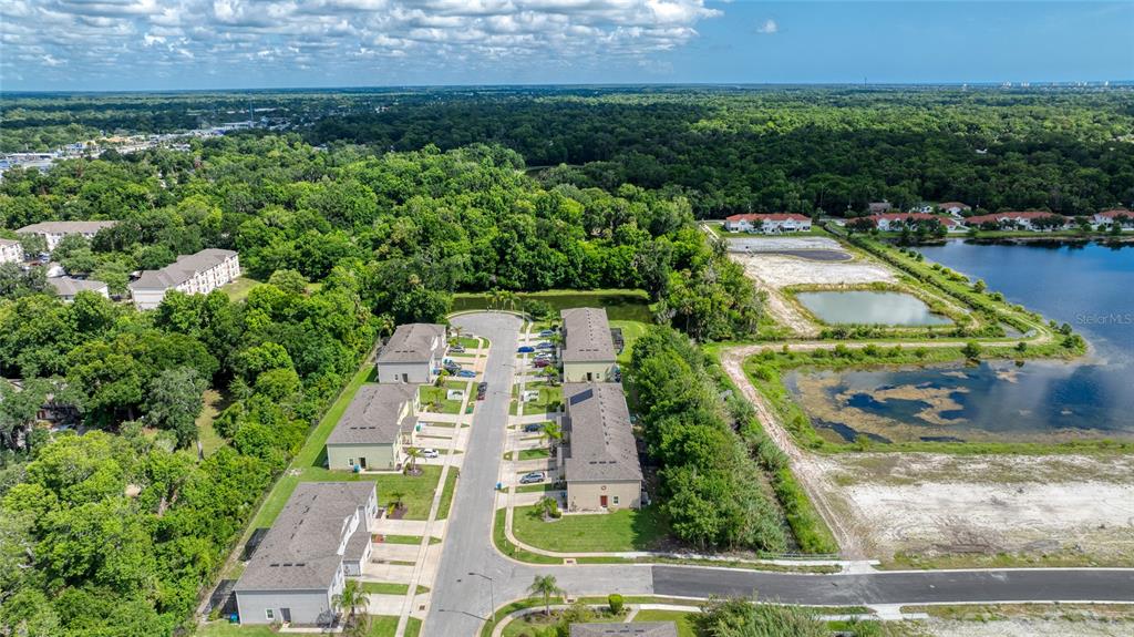 An aerial view shows a residential street with townhouses surrounded by trees and retention ponds — 1615 PRIMO COURT, DAYTONA BEACH, FL