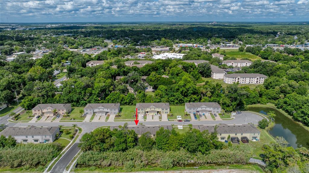 An aerial view shows a row of townhouses with a red arrow pointing to one unit — 1615 PRIMO COURT, DAYTONA BEACH, FL
