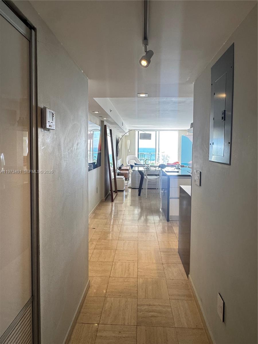 A tiled hallway leads into an open-concept living area with ocean views through floor-to-ceiling windows — 2457 Collins Ave # 405, Miami Beach FL 33140, MIAMI BEACH, FL