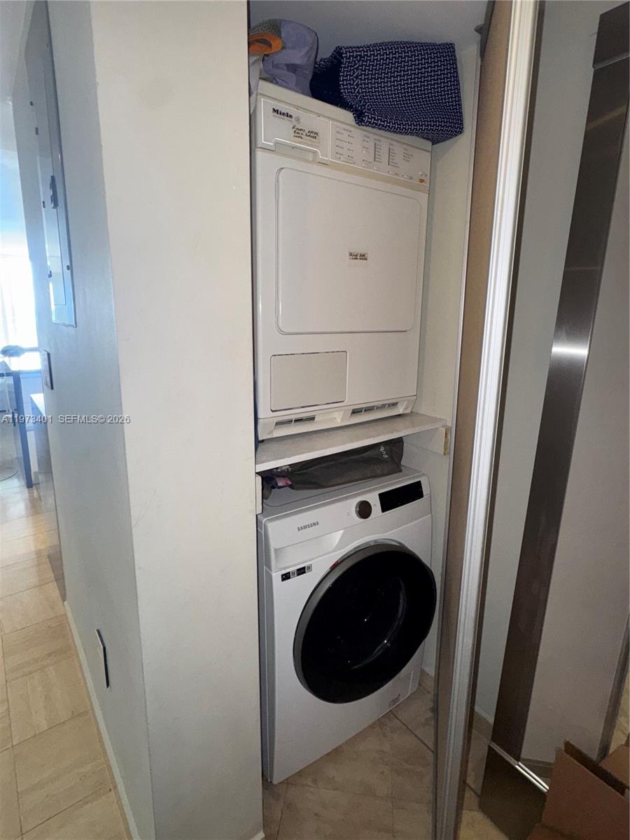 A stacked Miele dryer and Samsung washing machine are installed in a small laundry closet — 2457 Collins Ave # 405, Miami Beach FL 33140, MIAMI BEACH, FL