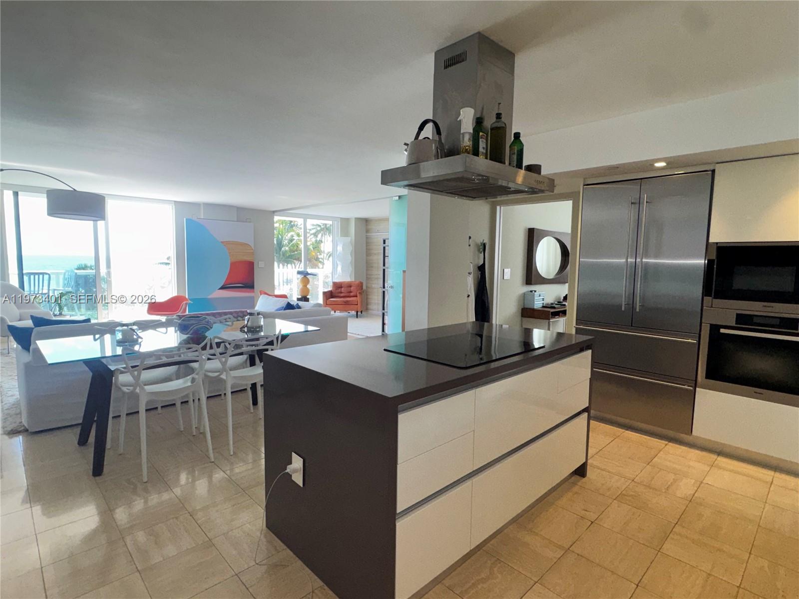 A modern kitchen features a central island with a cooktop and stainless steel appliances — 2457 Collins Ave # 405, Miami Beach FL 33140, MIAMI BEACH, FL