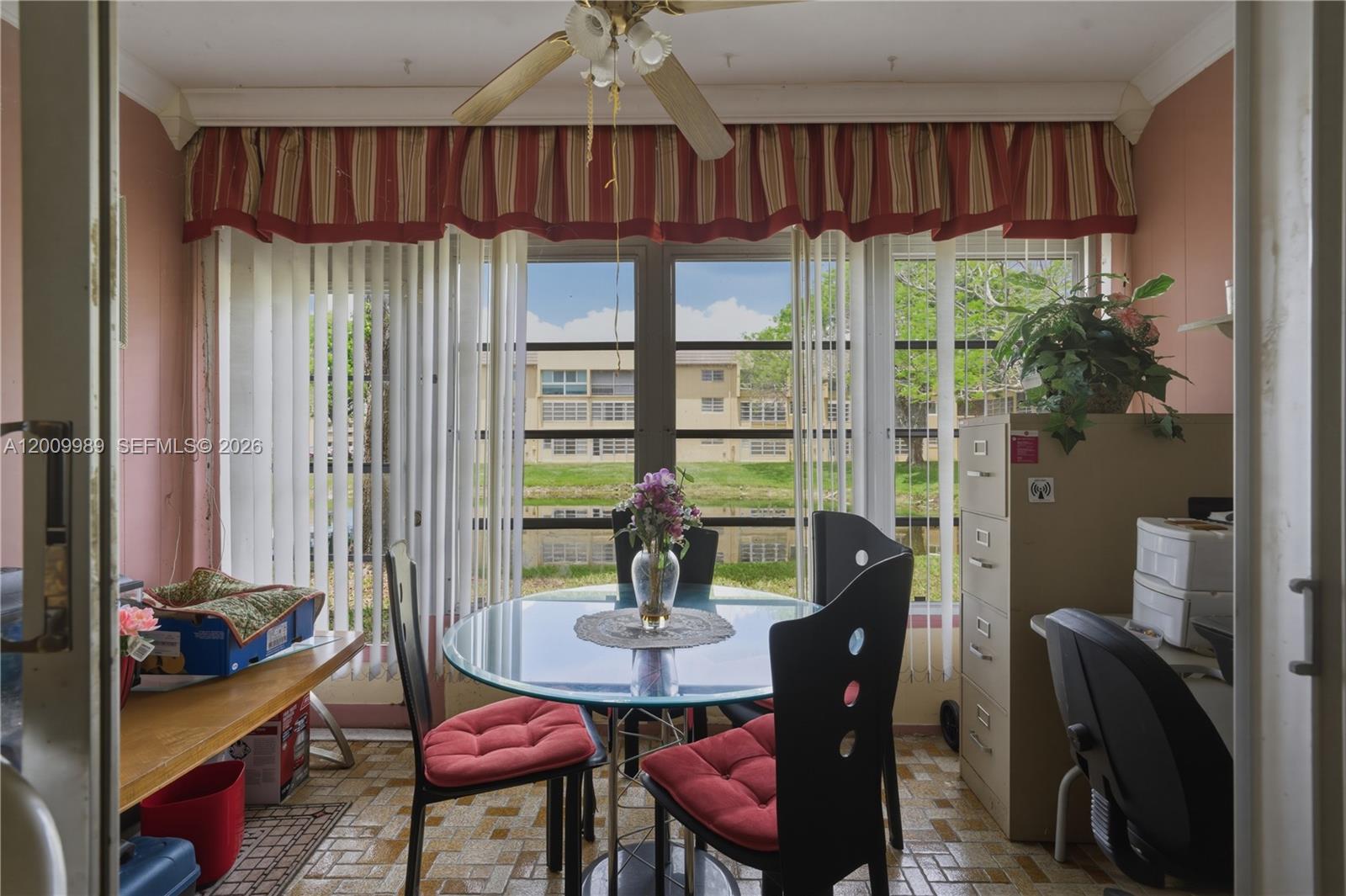 A dining area features a glass table, four chairs, and large windows overlooking a pond — 5961 NW 61st Ave # 111, Tamarac FL 33319, TAMARAC, FL