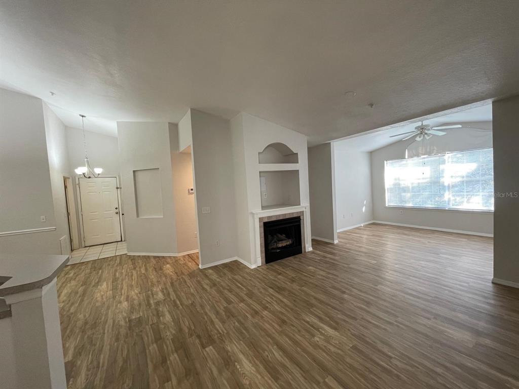 An open-concept living room features wood-look flooring, a fireplace with a built-in niche, and windows — 3313 S KIRKMAN ROAD UNIT 220, ORLANDO, FL
