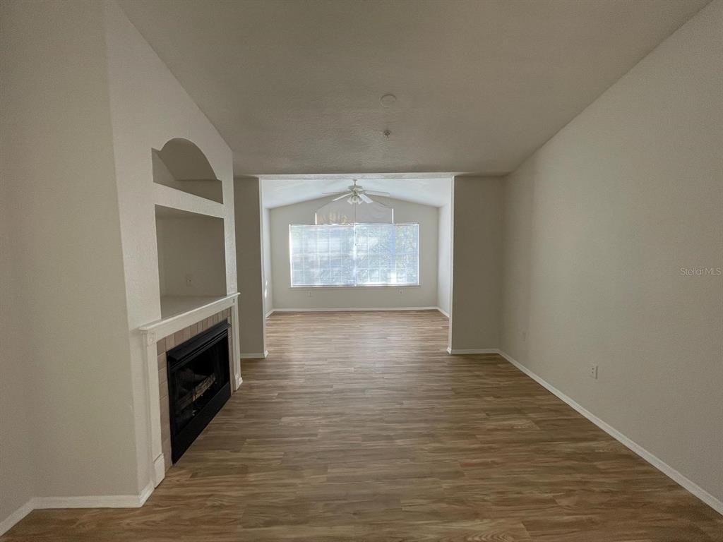 A living room with light wood-look flooring, a fireplace, and a ceiling fan — 3313 S KIRKMAN ROAD UNIT 220, ORLANDO, FL