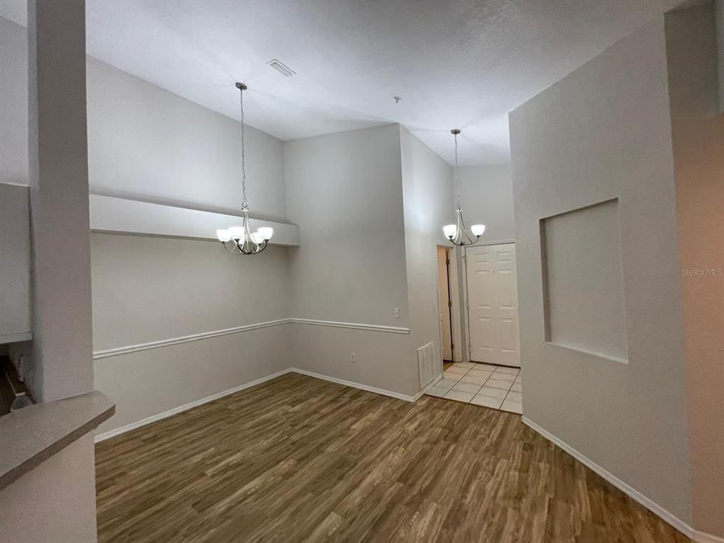 A dining area with wood-look flooring, two chandeliers, and a recessed wall niche — 3313 S KIRKMAN ROAD UNIT 220, ORLANDO, FL