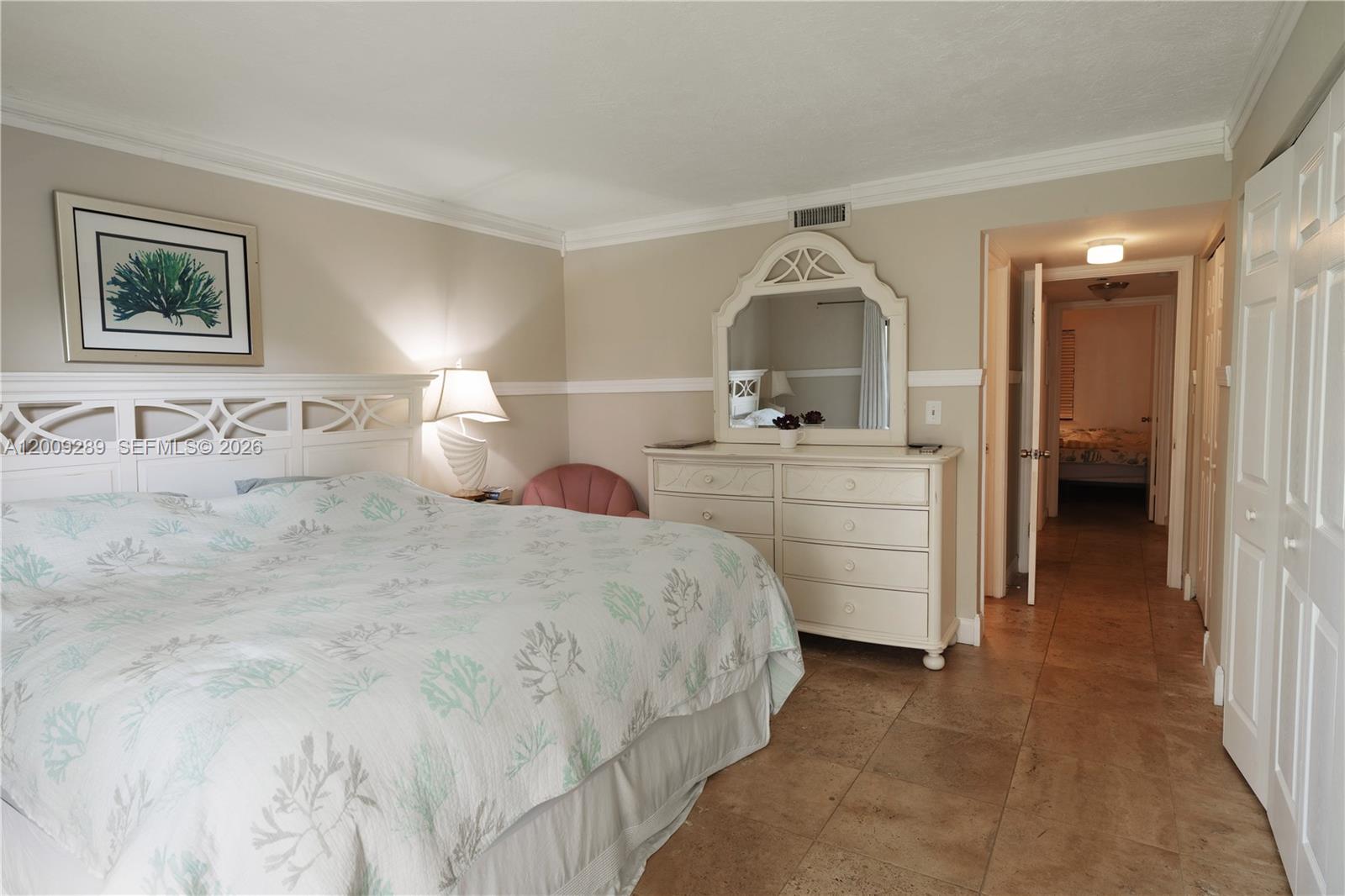 A bedroom features a white bed frame, a matching dresser with a mirror, and tile flooring — 420 Celestial Way # 101, Juno Beach FL 33408, JUNO BEACH, FL