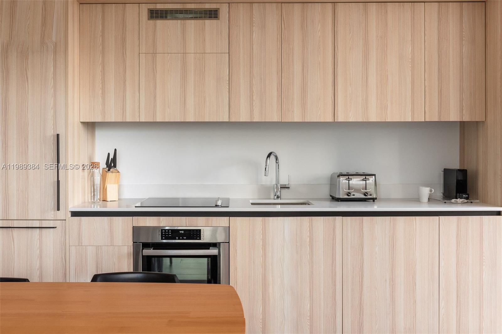 A modern studio apartment features a kitchenette, a desk, and a seating area by windows — 225 N Miami Ave # 202, Miami FL 33128, MIAMI, FL