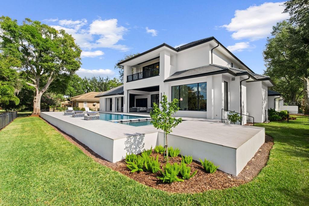 A two-story white modern house features a raised concrete patio and an outdoor swimming pool — 5074 ISLEWORTH COUNTRY CLUB DRIVE, WINDERMERE, FL