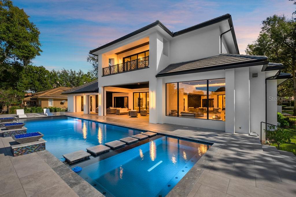 A modern two-story house with a swimming pool, stone patio, and large glass windows — 5074 ISLEWORTH COUNTRY CLUB DRIVE, WINDERMERE, FL
