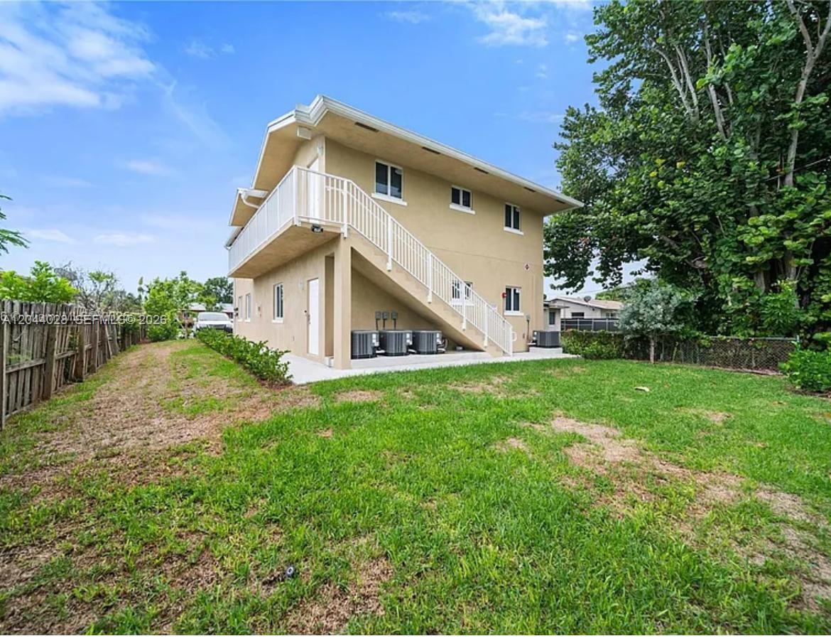 A two-story beige house features an exterior staircase leading to an upper-level balcony — 2311 Scott St # 2, Hollywood FL 33020, HOLLYWOOD, FL