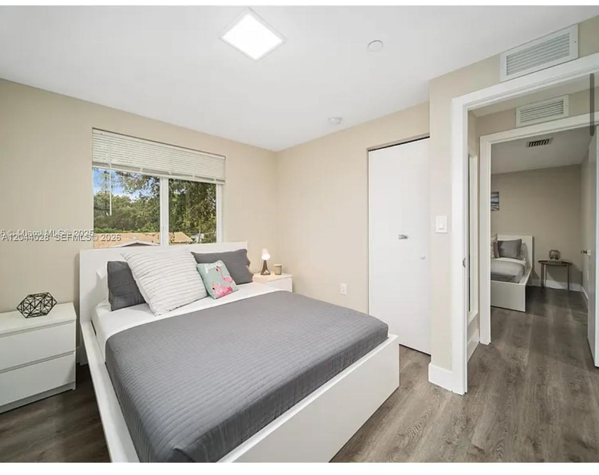 A bedroom with a white bed frame, gray bedding, and a doorway leading to another room — 2311 Scott St # 2, Hollywood FL 33020, HOLLYWOOD, FL