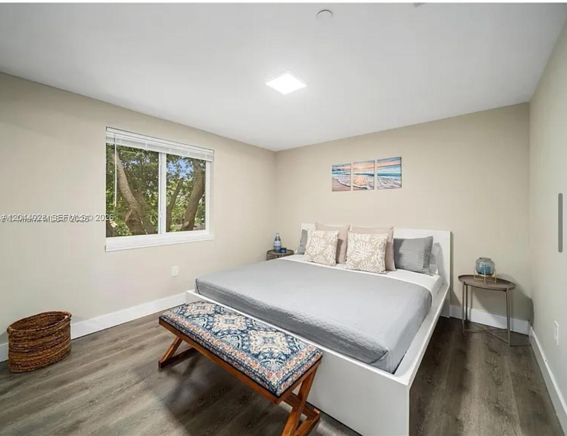 A bedroom features a white bed frame, gray bedding, a patterned bench, and wood-look flooring — 2311 Scott St # 2, Hollywood FL 33020, HOLLYWOOD, FL