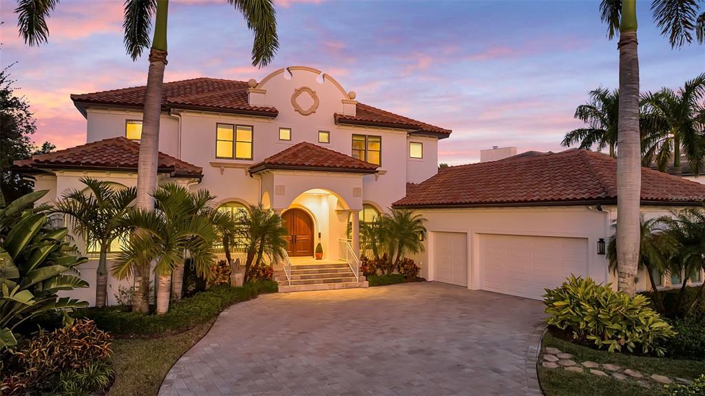 A two-story stucco house with a tile roof, arched entryway, and a paved driveway — 1389 TANGIER WAY, SARASOTA, FL