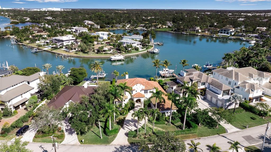 An aerial view shows a waterfront Mediterranean-style house with a tile roof and palm trees — 1389 TANGIER WAY, SARASOTA, FL