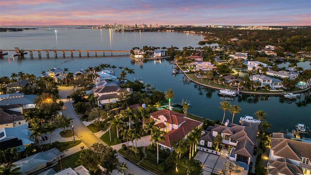 An aerial view of a waterfront residential neighborhood with a bridge and city skyline — 1389 TANGIER WAY, SARASOTA, FL