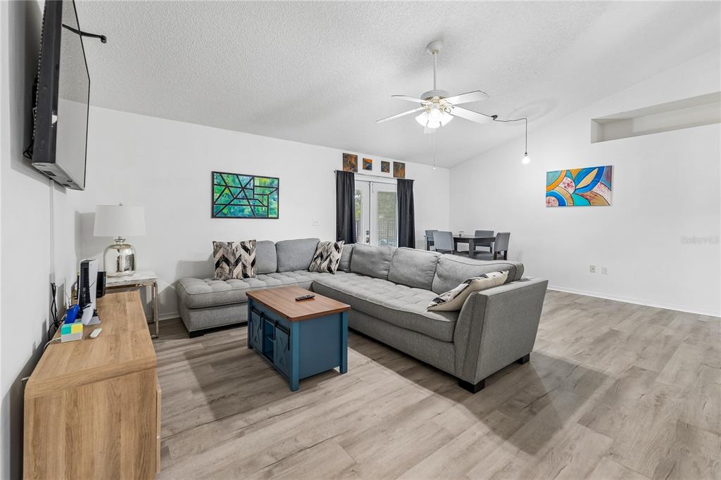 A living room features gray sectional seating, a blue coffee table, and light wood flooring — 5730 LOMA VISTA DRIVE W, DAVENPORT, FL