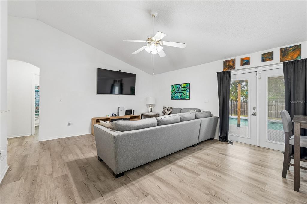 A living room features light wood-look flooring, a gray sectional sofa, and a ceiling fan — 5730 LOMA VISTA DRIVE W, DAVENPORT, FL