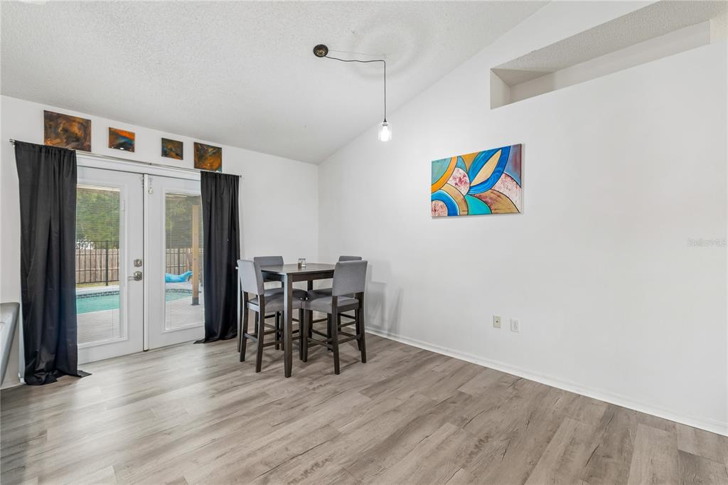 A dining area with wood-look flooring, a small table, four chairs, and sliding glass doors — 5730 LOMA VISTA DRIVE W, DAVENPORT, FL
