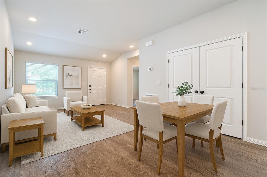 A living and dining area features light wood-look flooring, white walls, and neutral furniture — 1201 SE 24TH AVENUE, CAPE CORAL, FL
