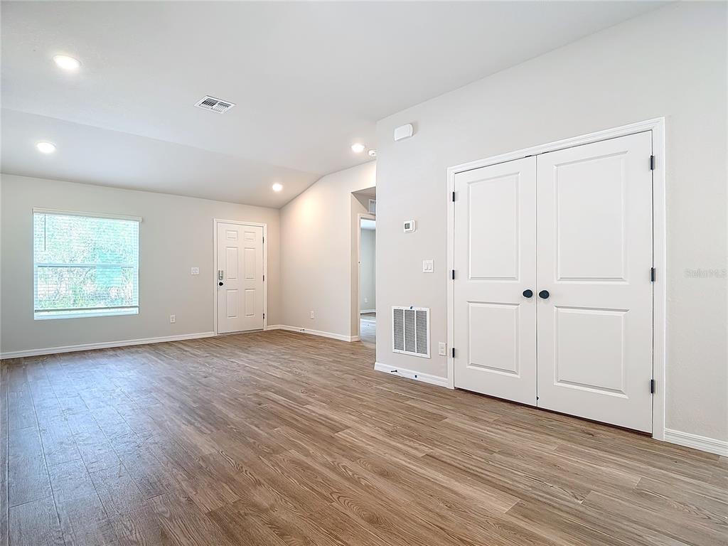 A bright room features light-colored walls, wood-look flooring, a window, and double closet doors — 1201 SE 24TH AVENUE, CAPE CORAL, FL