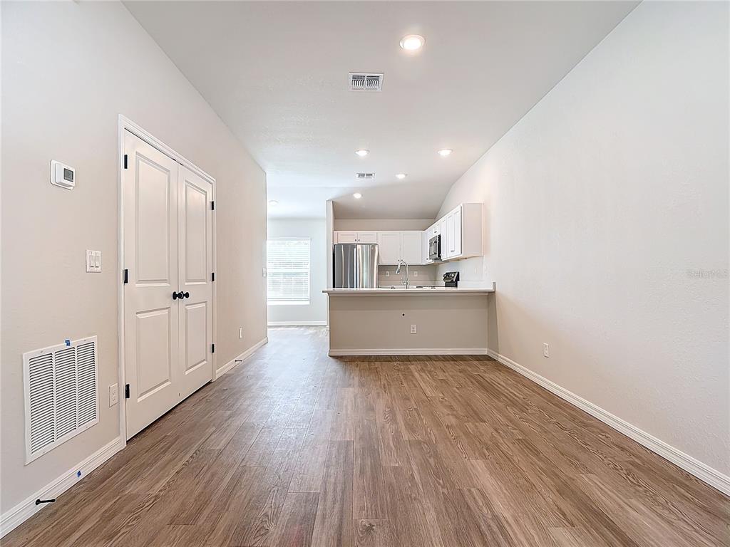 A view of an open-concept kitchen and living area with wood-look flooring and white cabinetry — 1201 SE 24TH AVENUE, CAPE CORAL, FL