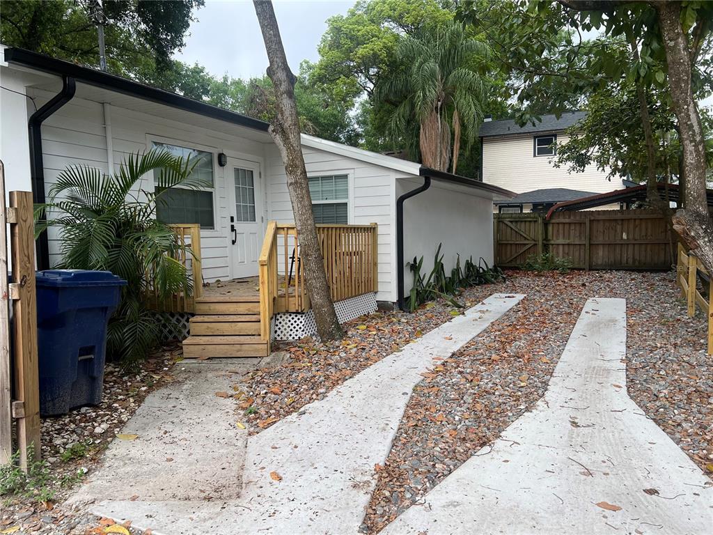 A white house with a wooden deck and a concrete driveway covered in fallen leaves — 311 E FLORIBRASKA AVENUE, TAMPA, FL