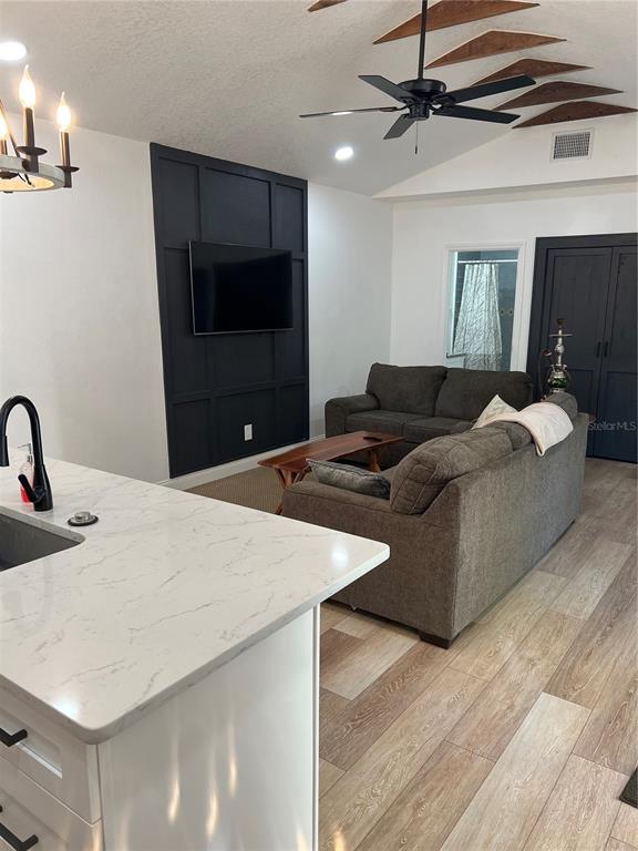 A living room features a dark accent wall with a television and wood-look flooring — 311 E FLORIBRASKA AVENUE, TAMPA, FL