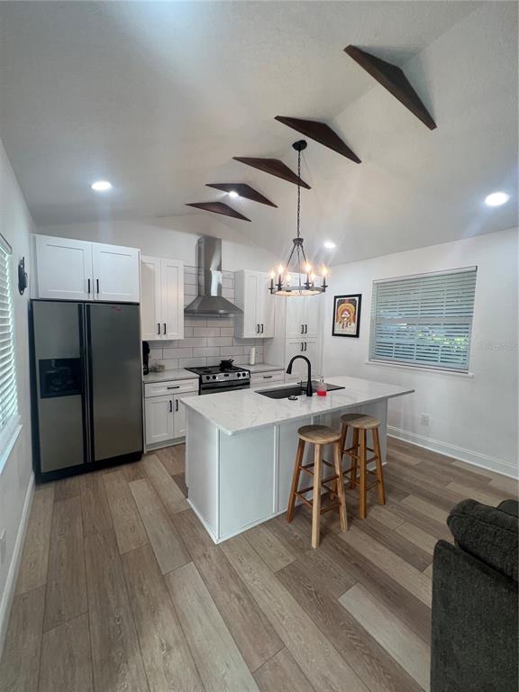 A modern kitchen features white cabinetry, a marble-topped island, and decorative wooden ceiling beams — 311 E FLORIBRASKA AVENUE, TAMPA, FL