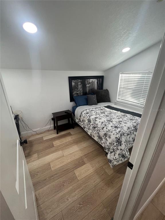 A bedroom with a bed, a nightstand, and wood-look flooring under a sloped ceiling — 311 E FLORIBRASKA AVENUE, TAMPA, FL