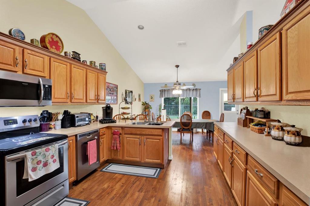 A kitchen with wood cabinets, stainless steel appliances, and a dining area in the background — 9086 MANCHESTER STREET, SPRING HILL, FL