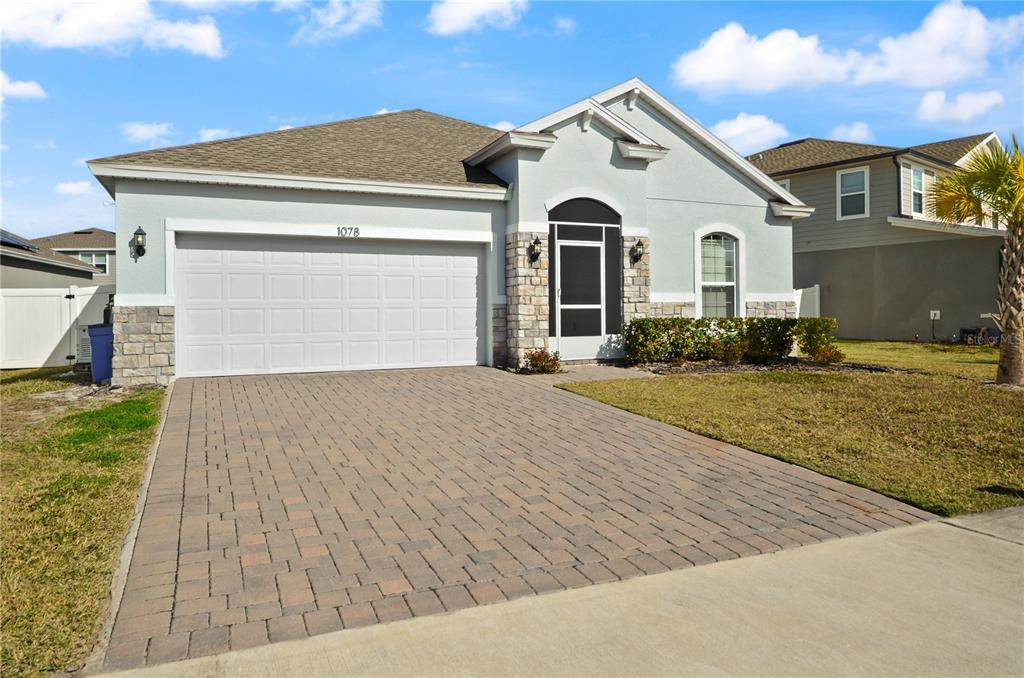 A single-story house with a paved driveway, stone accents, and a screened front entryway — 1078 CHELAN FALLS DRIVE, DELAND, FL